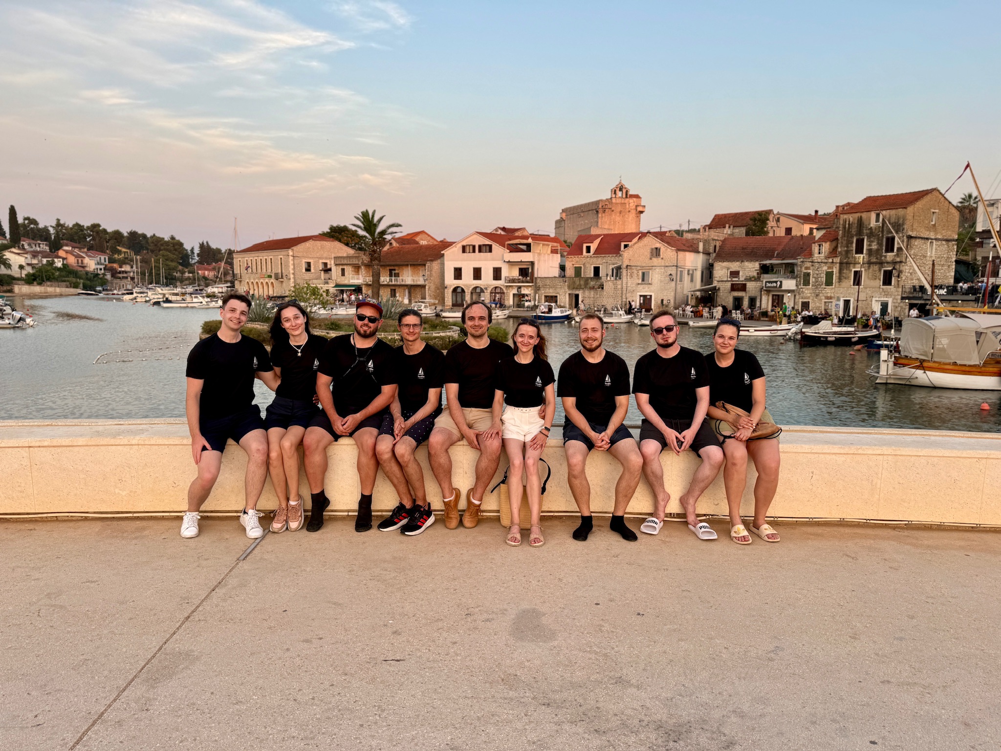 skupina lidí sedící na římse u vodní plochy