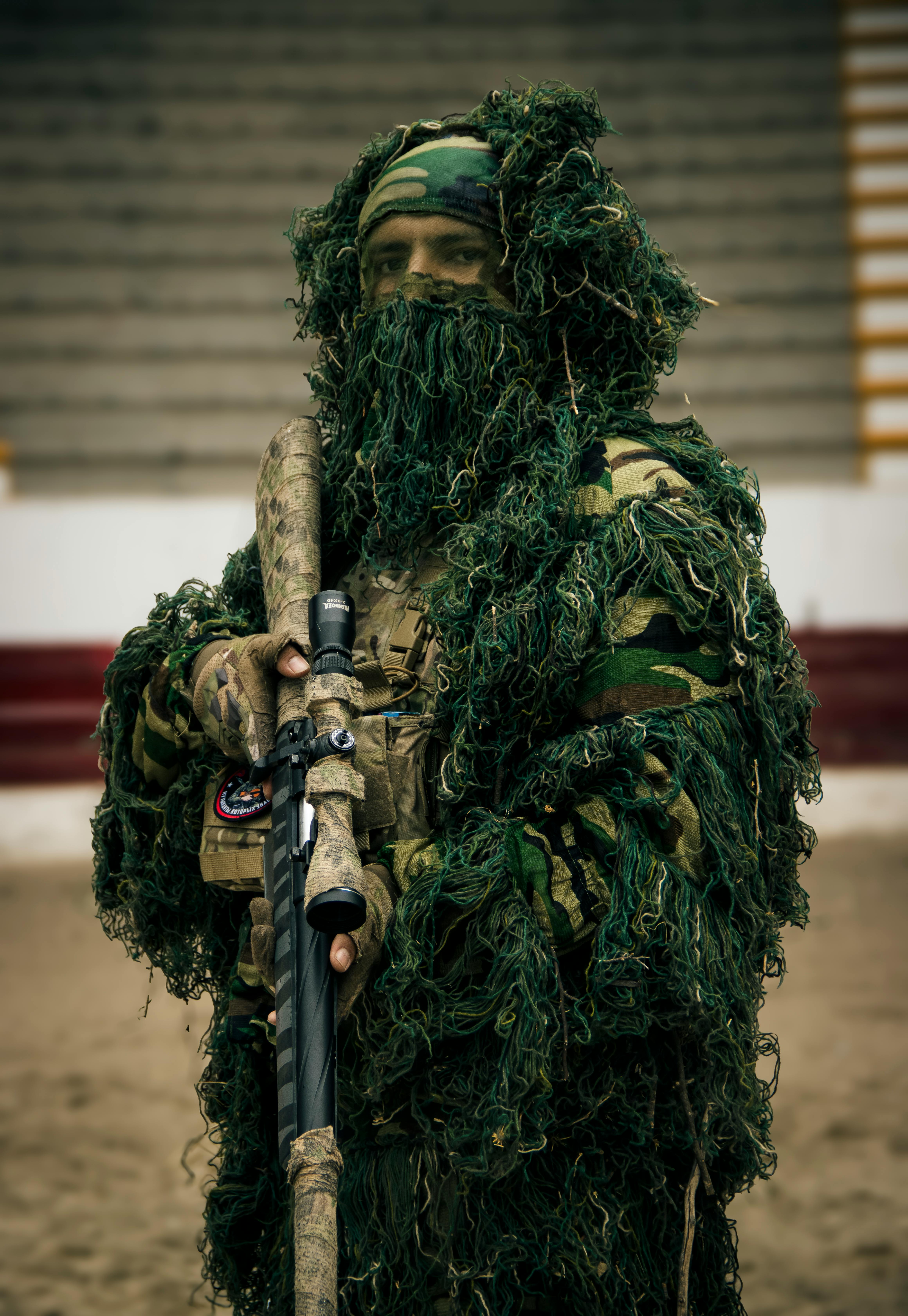 osoba v maskáčích se zbraní