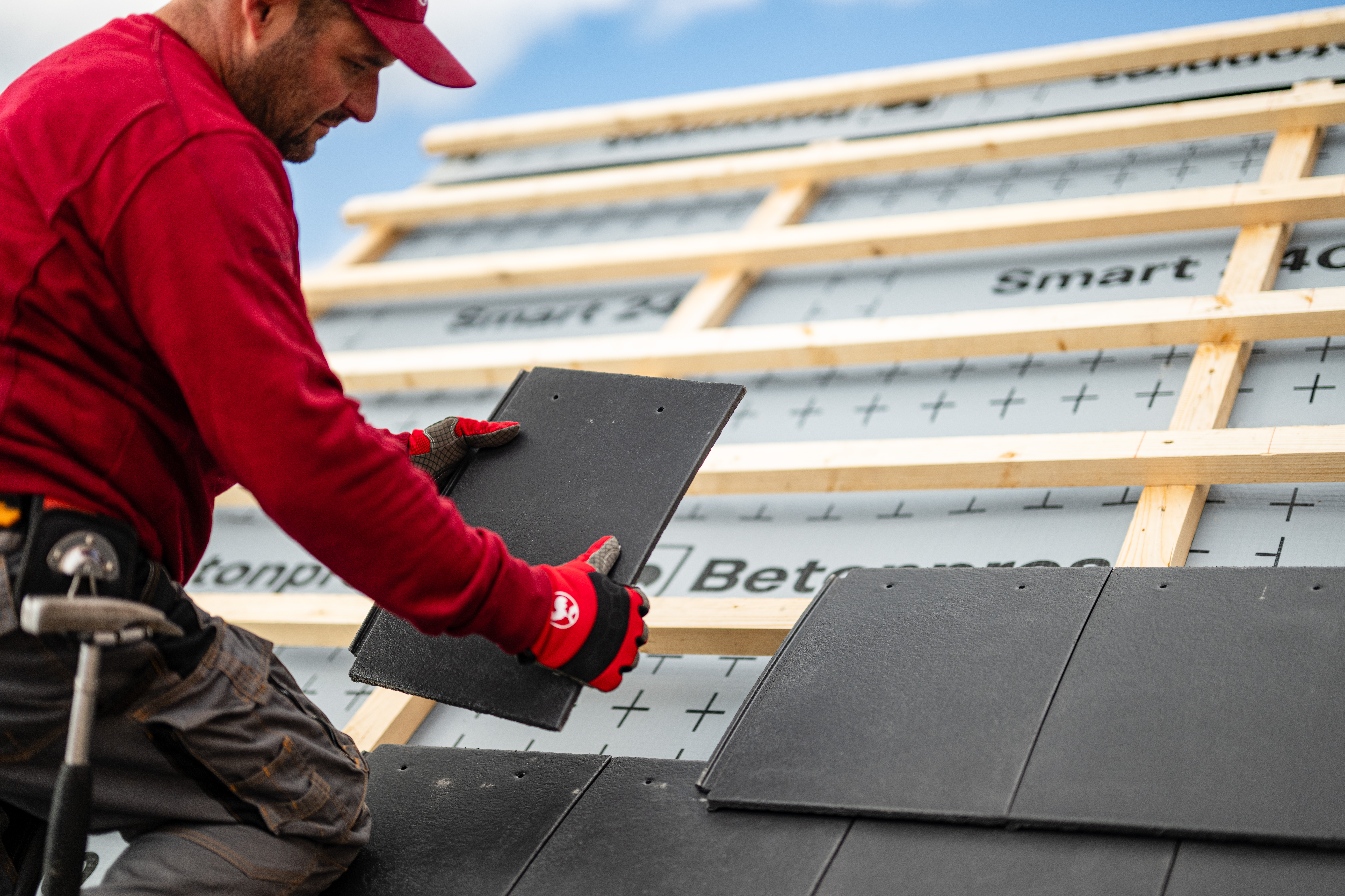 Osoba v červené čepici a rukavicích, držící černé dlaždice